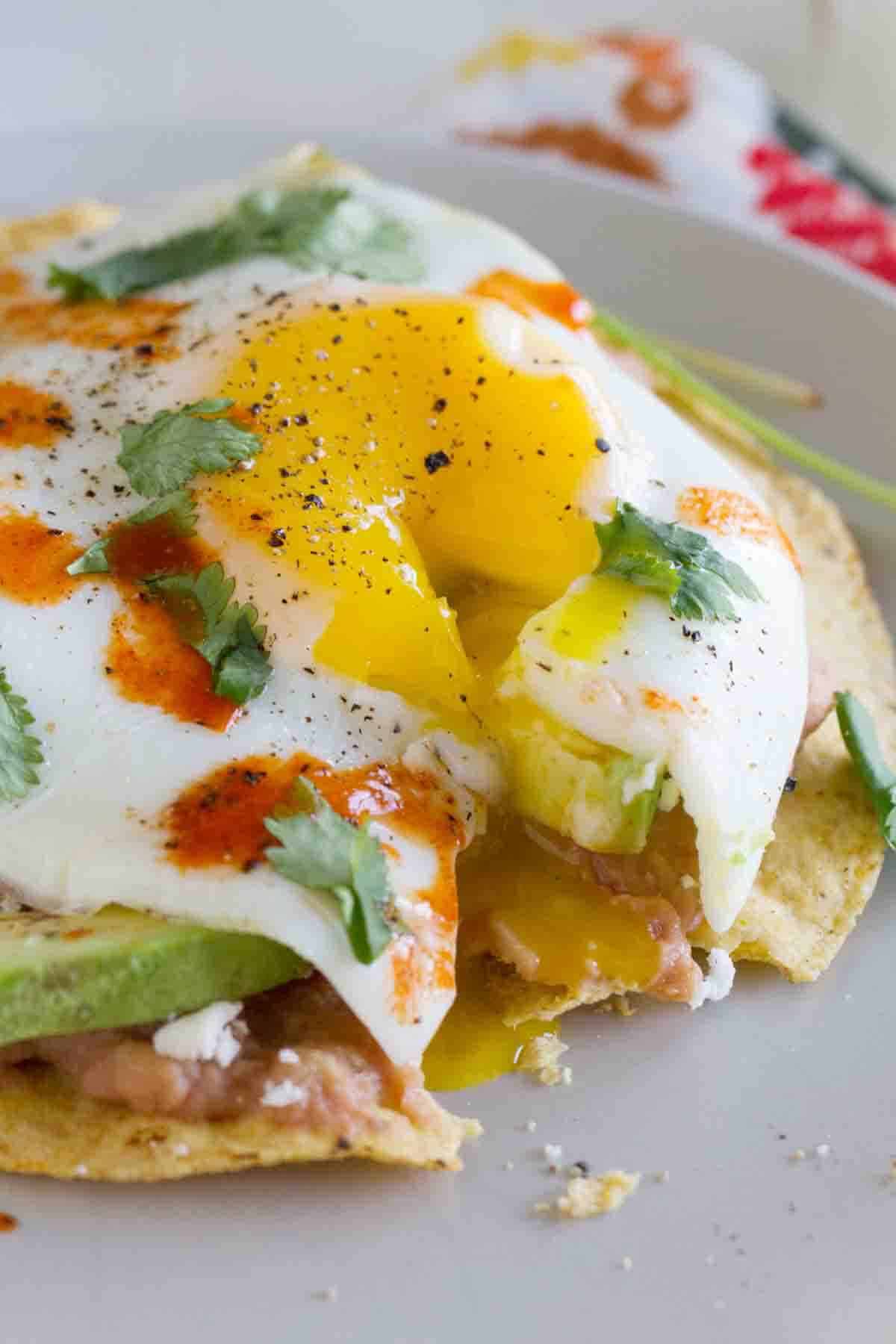 Breakfast Tostada with a bite taken from it to show egg dripping down.