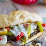 Cheesesteak sandwich with cheese sauce and peppers.