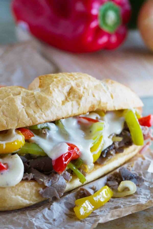 Cheesesteak sandwich with cheese sauce and peppers.