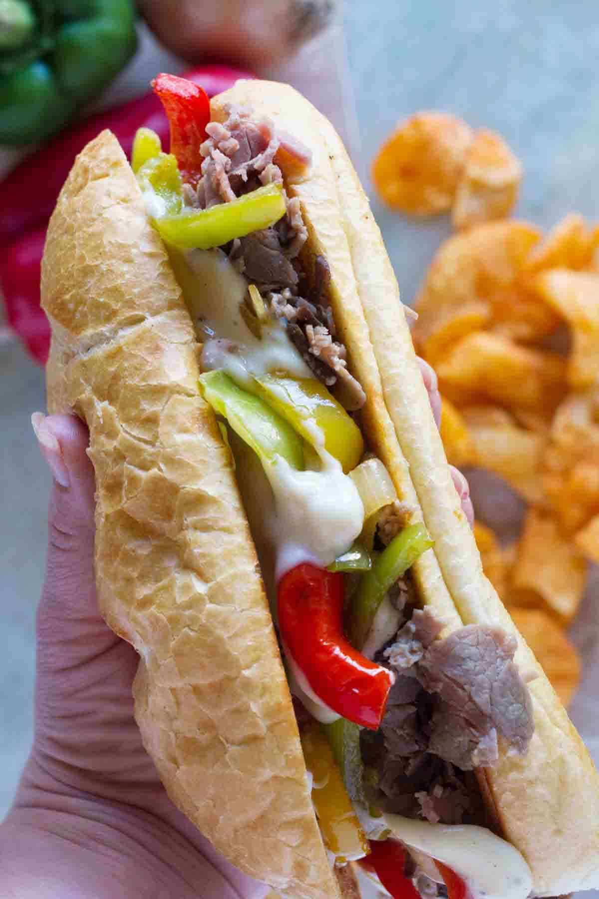 hand holding a cheesesteak sandwich.