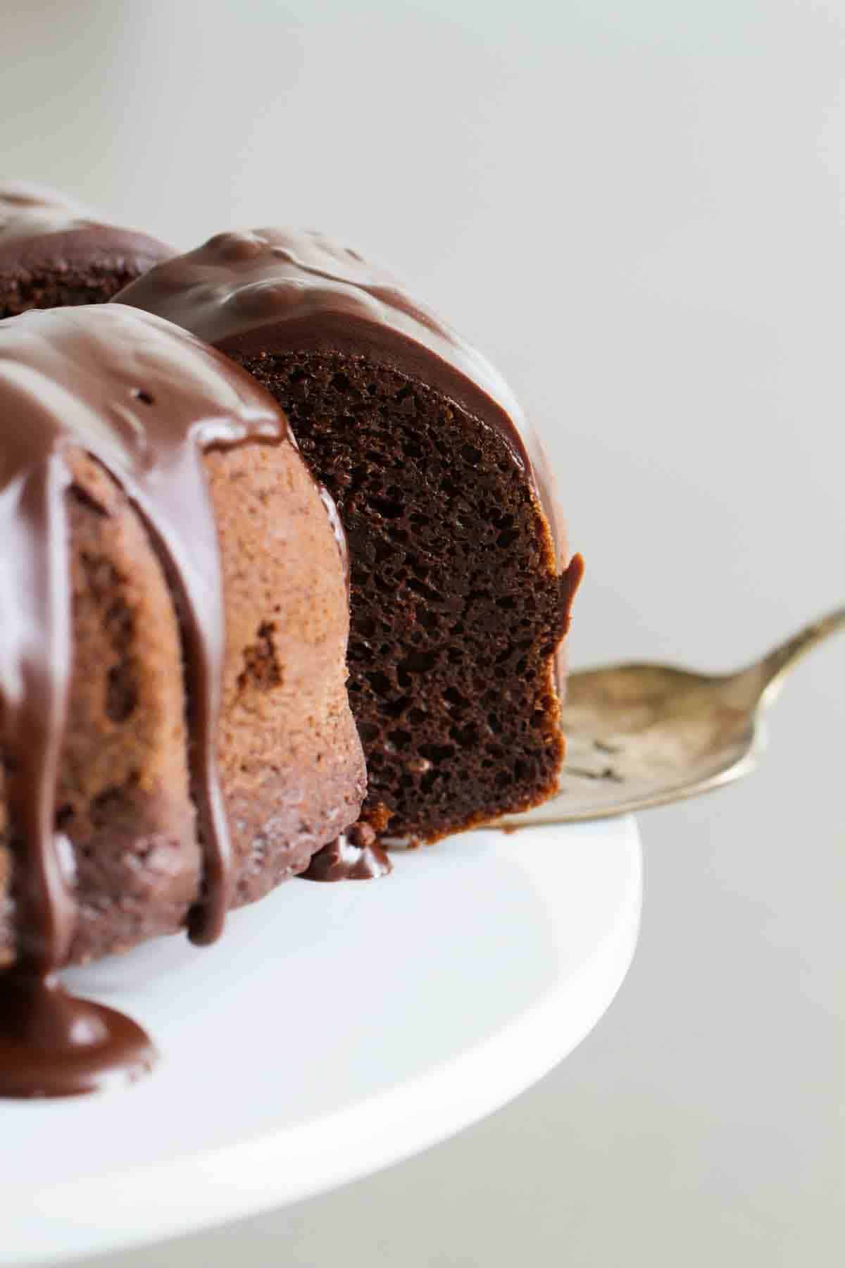 Removing a slice of chocolate bundt cake from the whole cake.