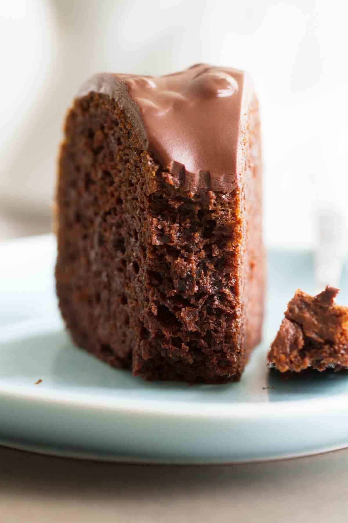 Slice of chocolate bundt cake with chocolate glaze with a fork full taken from it to show texture.