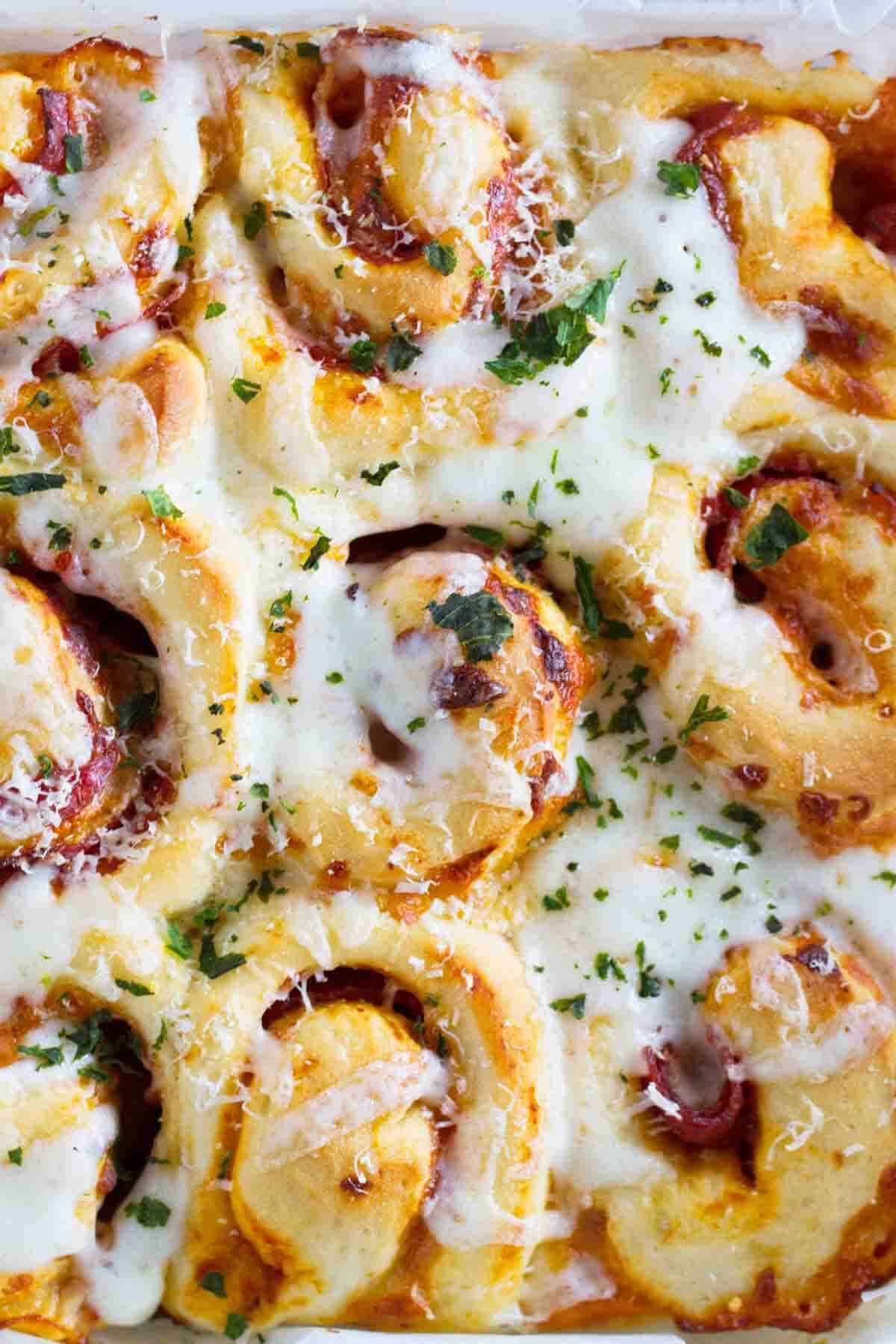 Pizza rolls covered in cheese and herbs.