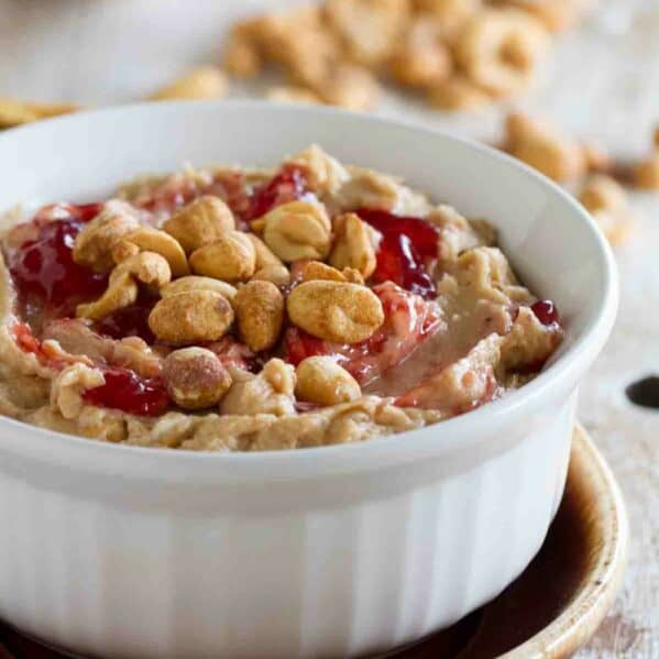 Bowl with peanut butter and jelly dip topped with peanuts and jelly.