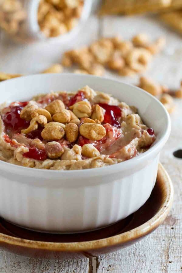 Bowl with peanut butter and jelly dip topped with peanuts and jelly.