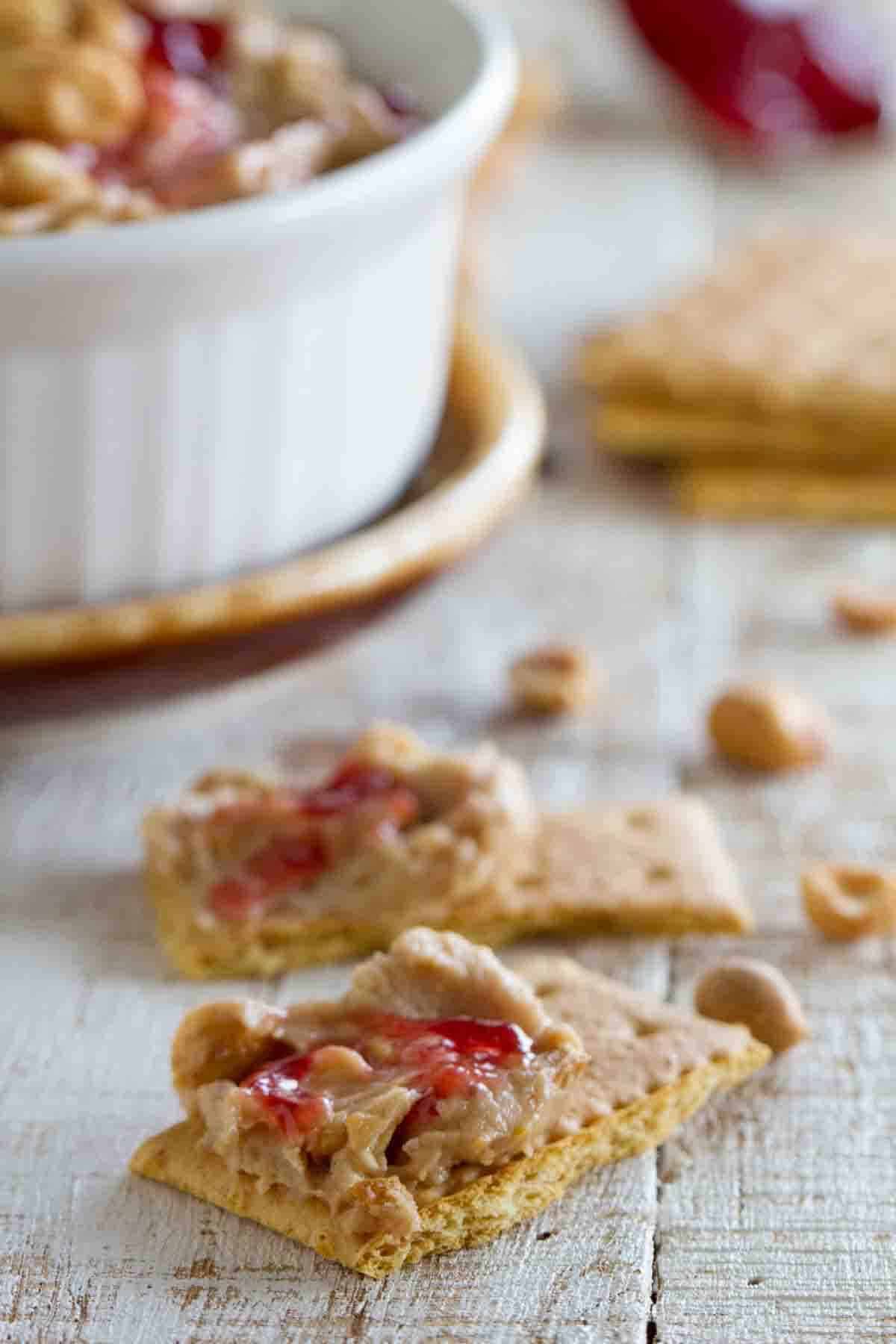 Graham cracker pieces topped with peanut butter and jelly dip.