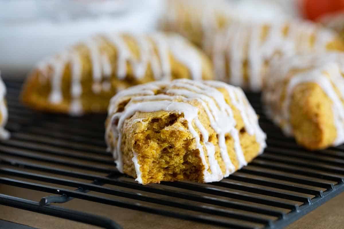 Pumpkin Scones on a cooling rack with a bite taken from one showing the texture.