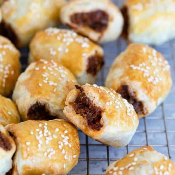 Sausage Rolls on a cooling rack, stacked next to each other.