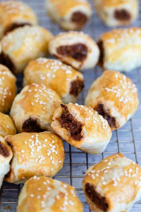 Sausage Rolls on a cooling rack, stacked next to each other.