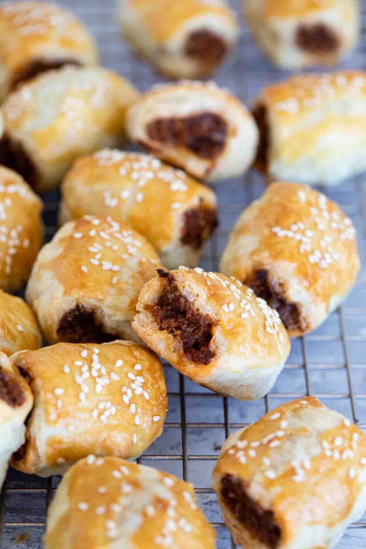 Sausage Rolls on a cooling rack, stacked next to each other.