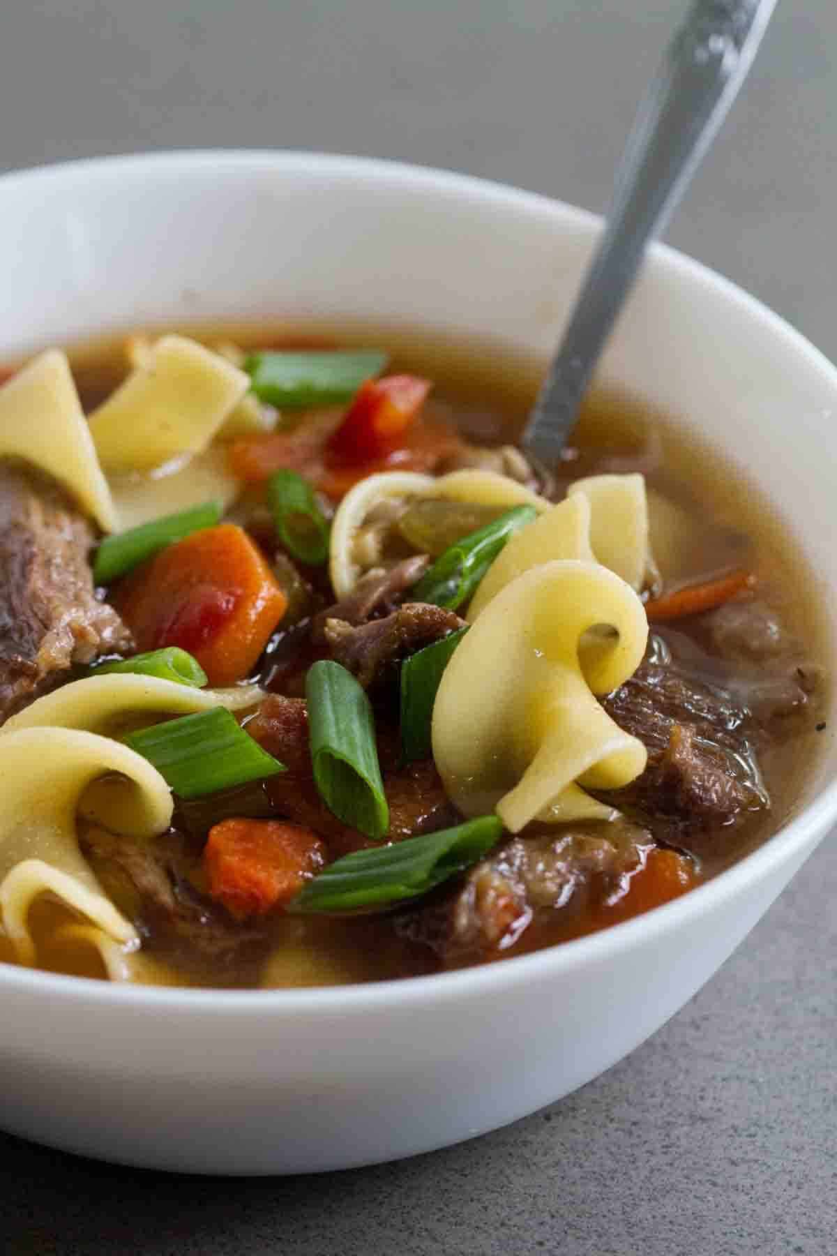 Bowl of Slow Cooker Beef Noodle Soup with a spoon.