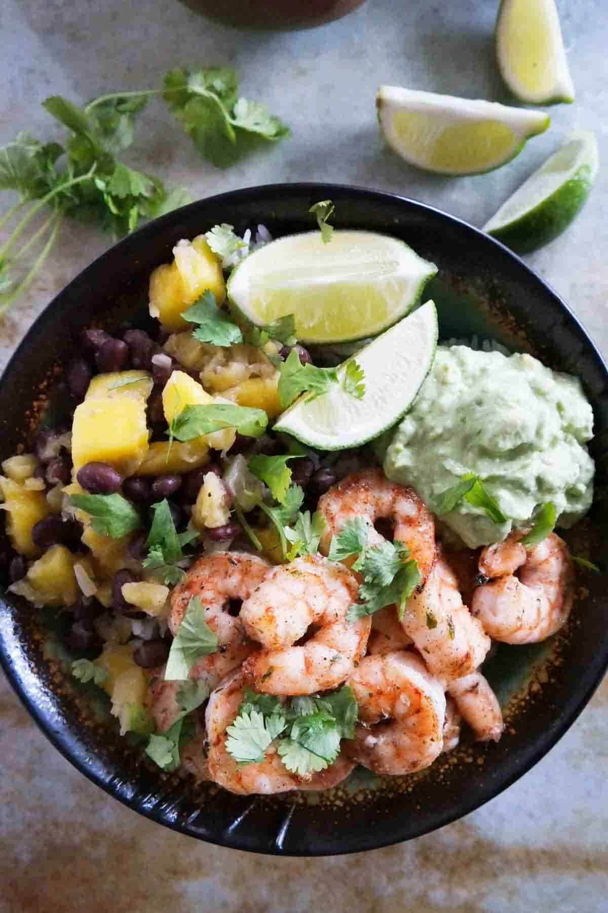 Spicy Shrimp Bowls - coconut rice topped with shrimp, beans, mango, pineapple, and mashed avocado.
