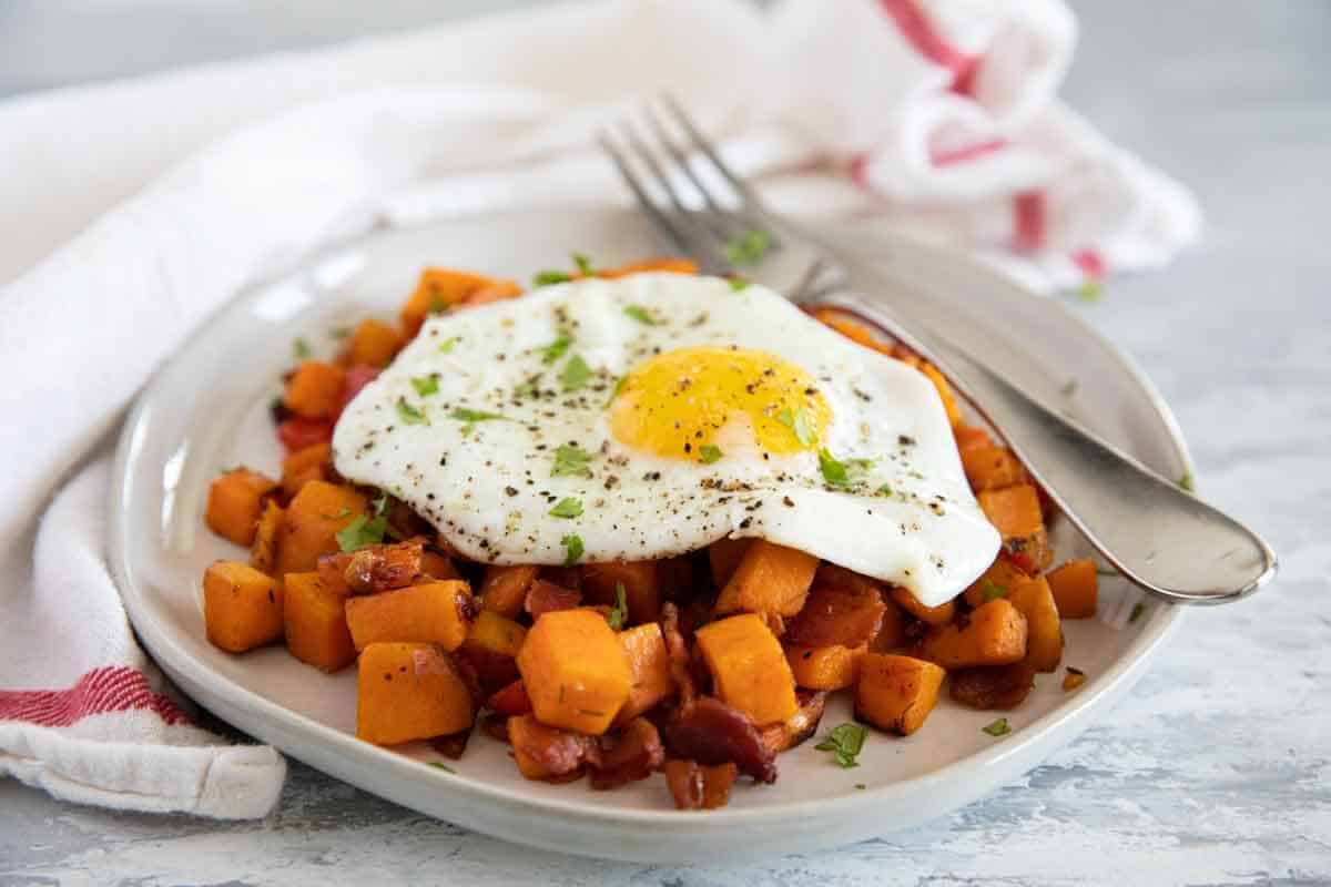 Plate with sweet potato hash topped with an over easy egg.