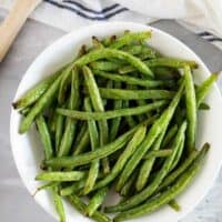 Bowl of green beans cooked in the air fryer in a bowl.