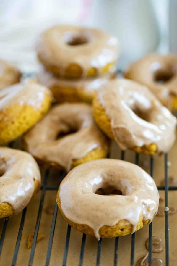 Baked pumpkin donuts stacked on a cooling rack.