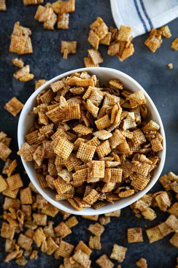 Bowl full of cinnamon caramel snack mix with more outside the bowl.