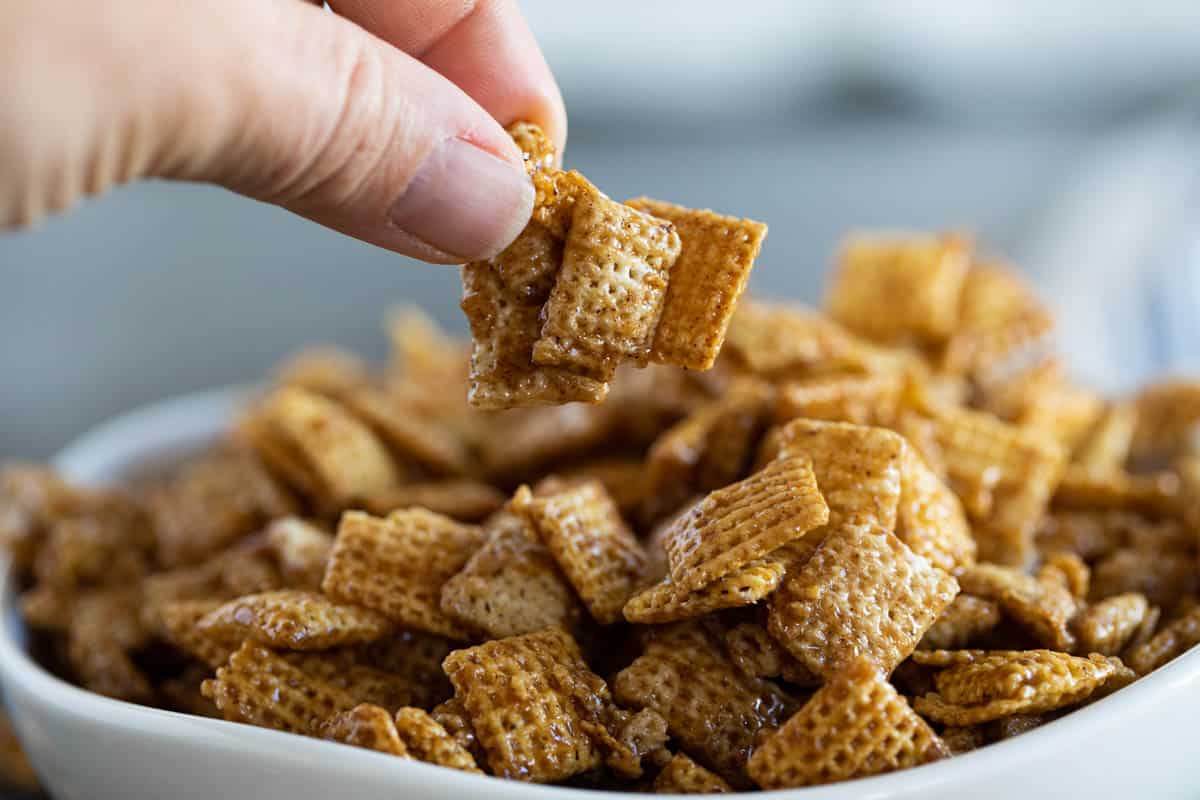 Fingers picking up some Cinnamon Caramel Snack Mix