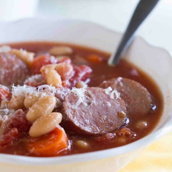 bowl of white bean soup with smoked sausage with a spoon in the bowl.