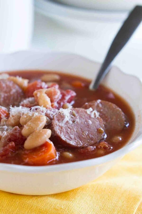 bowl of white bean soup with smoked sausage with a spoon in the bowl.