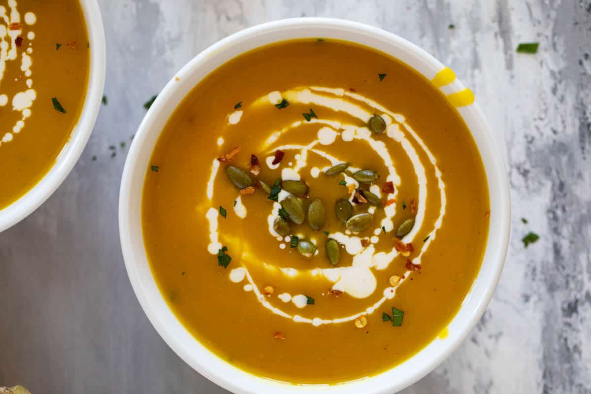 Bowls of Curried Butternut Squash soup with parsley, pepitas, and cream.