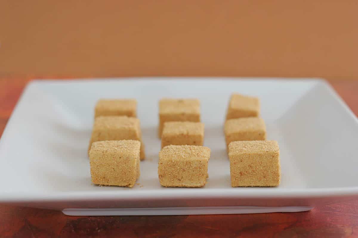 The perfect addition to that fall cup of cocoa or for a fall charcuterie board, these Pumpkin Spice Marshmallows are so delicious and so festive! Nine pumpkin spice marshmallows on a white plate.
