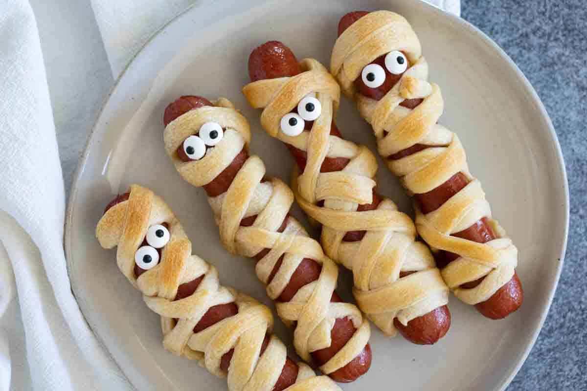 Four Mummy Hot Dogs on a plate.