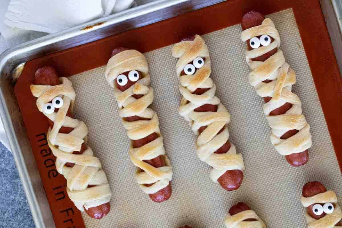 Mummy hot dogs on a baking sheet.