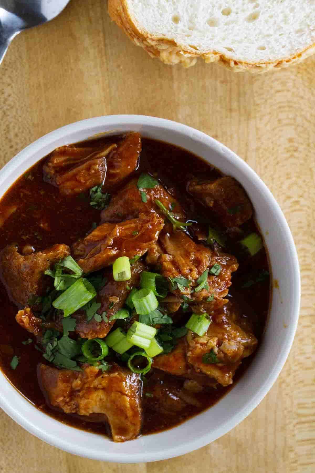 Bowl of New Mexican Red Pork Chili topped with green onions and cilantro.