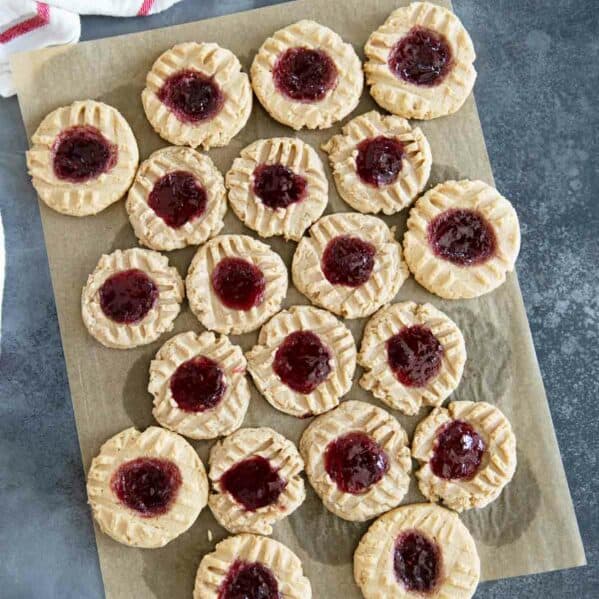 Peanut Butter and Jelly Thumbprint Cookies on a piece of brown parchment paper.