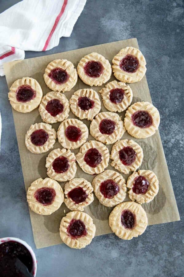 Peanut Butter and Jelly Thumbprint Cookies on a piece of brown parchment paper.