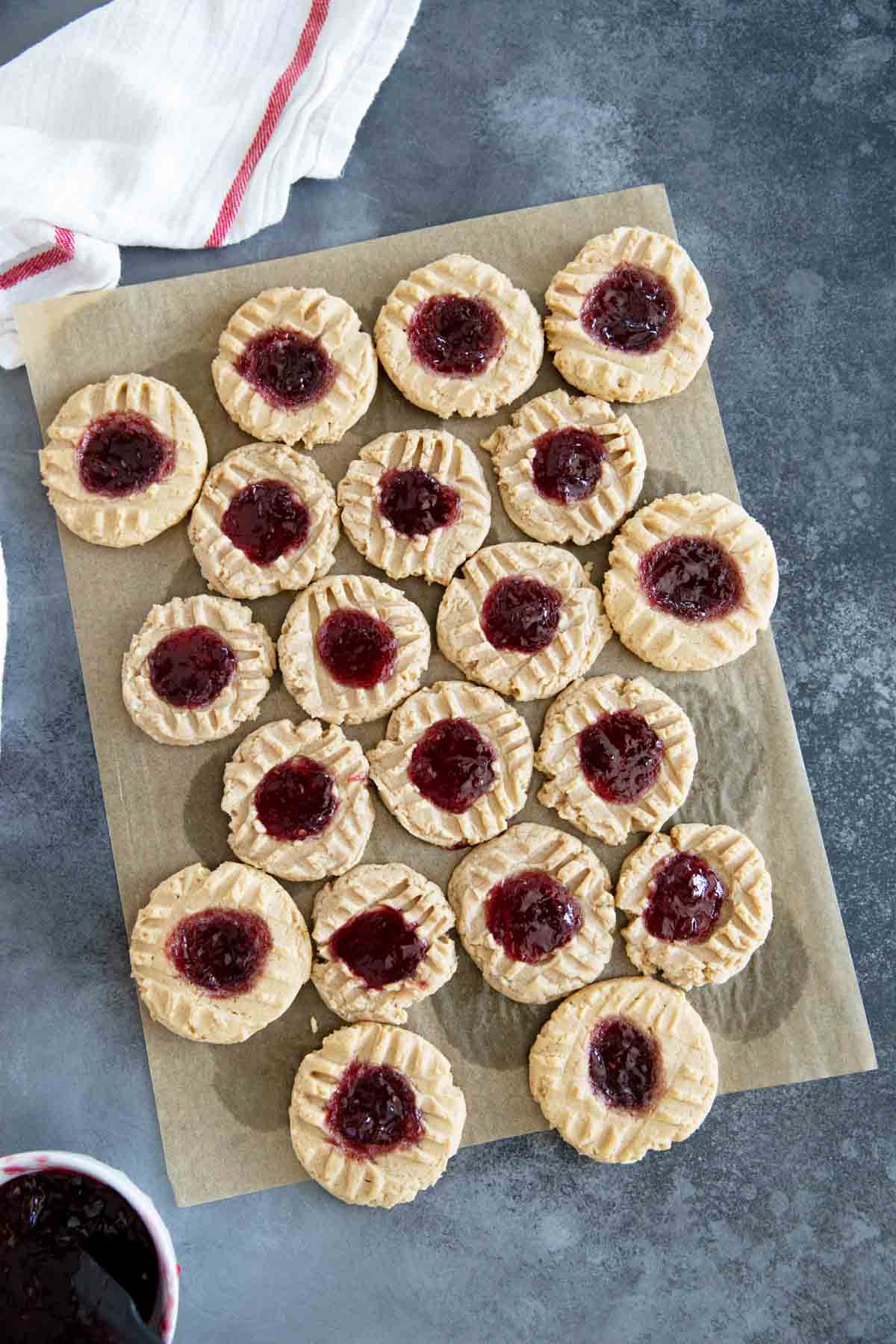 Peanut Butter and Jelly Thumbprint Cookies on a piece of brown parchment paper.