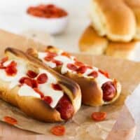 Two pizza dogs topped with cheese and pepperoni.