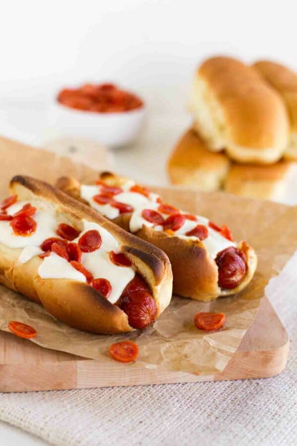 Two pizza dogs topped with cheese and pepperoni.