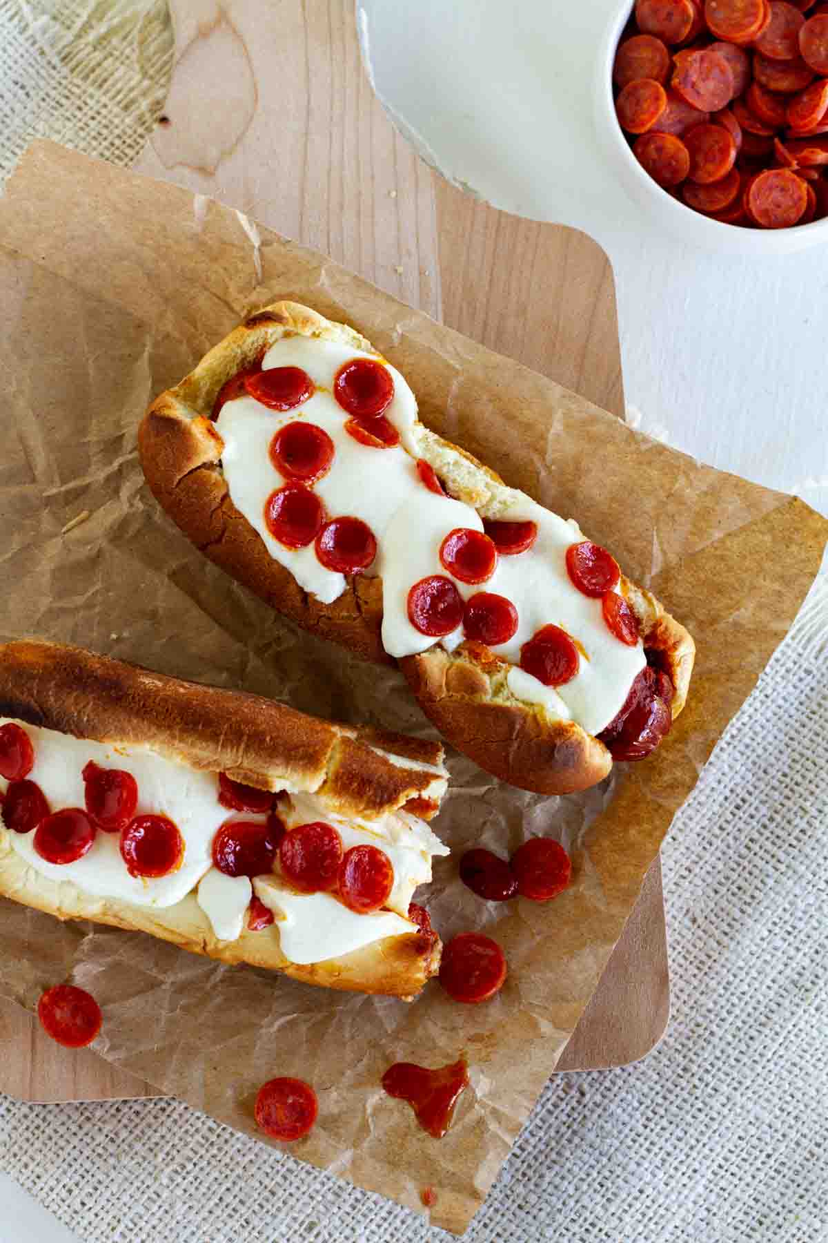 Two pizza hot dogs topped with mini pepperoni.