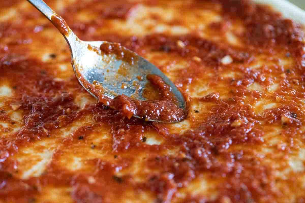 Spreading pizza sauce with a spoon.