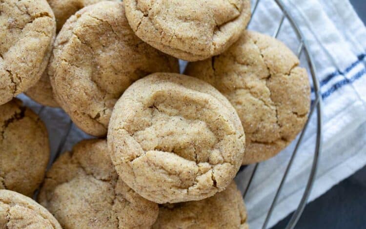 Pumpkin snickerdoodle cookies stacked on each other on a wire rack.