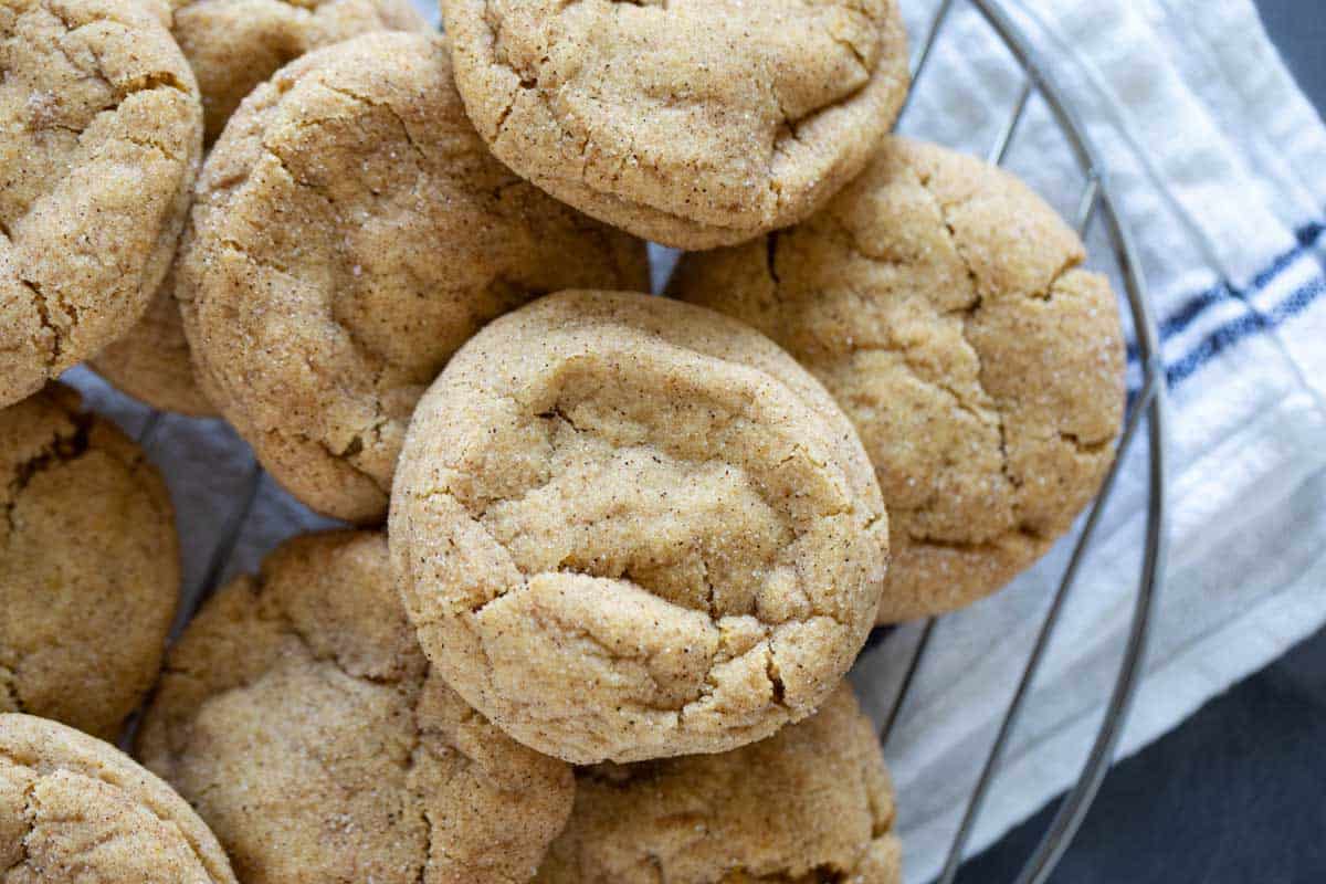 Pumpkin snickerdoodle cookies stacked on each other on a wire rack.