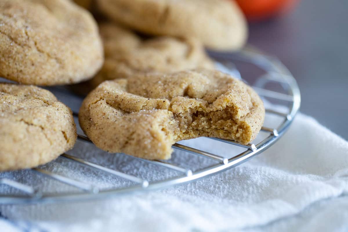 Soft and chewy with the perfect amount of pumpkin spice, these Pumpkin Snickerdoodles are a fall time favorite! Pumpkin snickerdoodle with a bite taken from it.