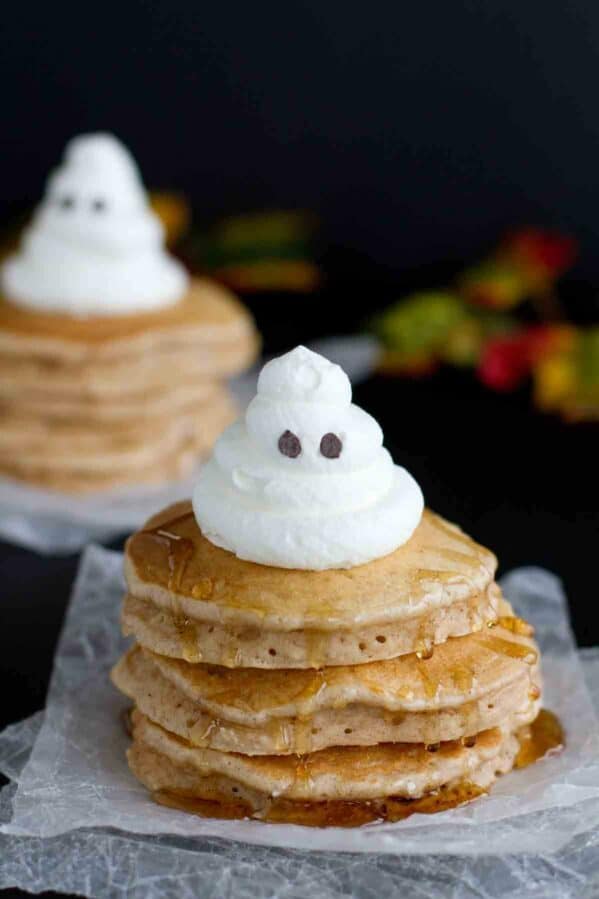 Stack of spiced ghost pancakes with a whipped cream ghost on top.