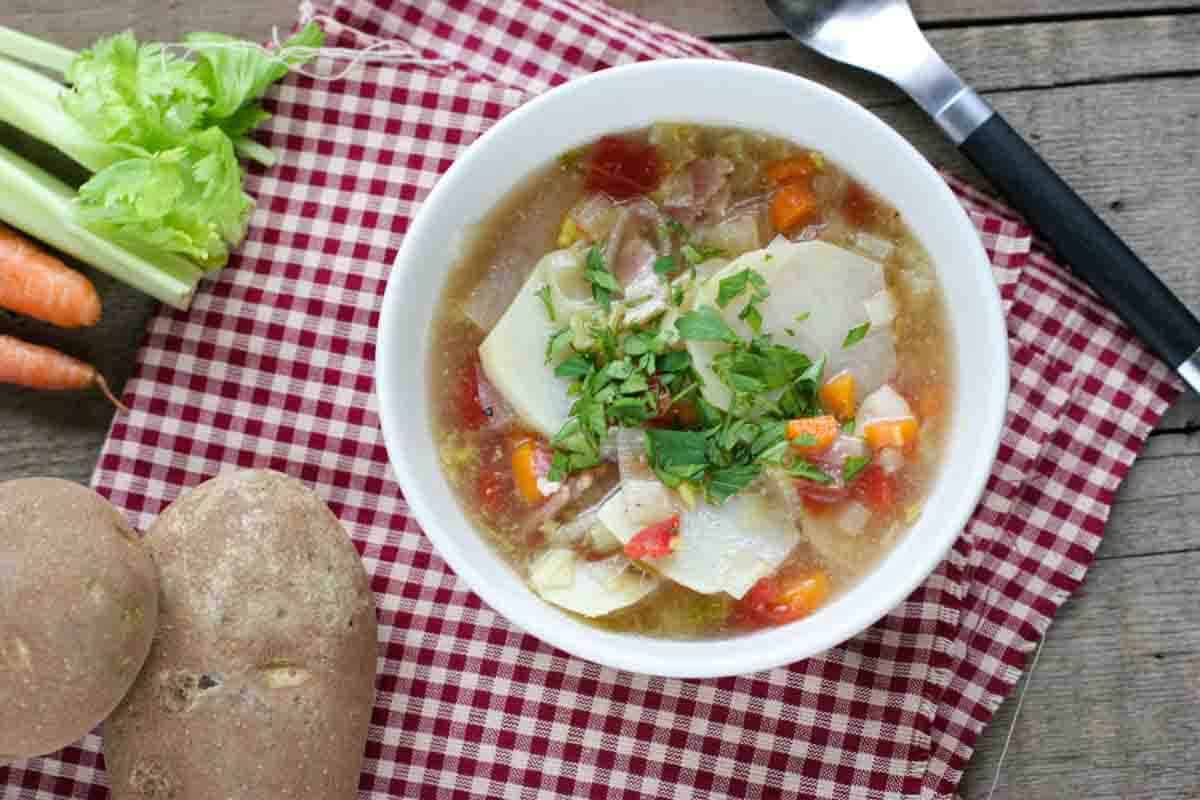 Bowl of Tomato and Potato Soup surrounded by ingredients.