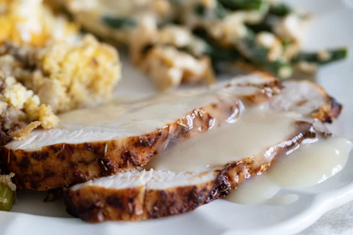 Sliced air fryer turkey breast on a plate with gravy.