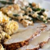 Slices of air fryer turkey breast with gravy on a plate with side dishes.