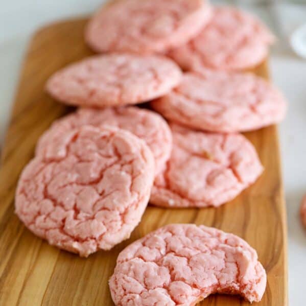 Cake mix cookies made from strawberry cake mix stacked on a cutting board.