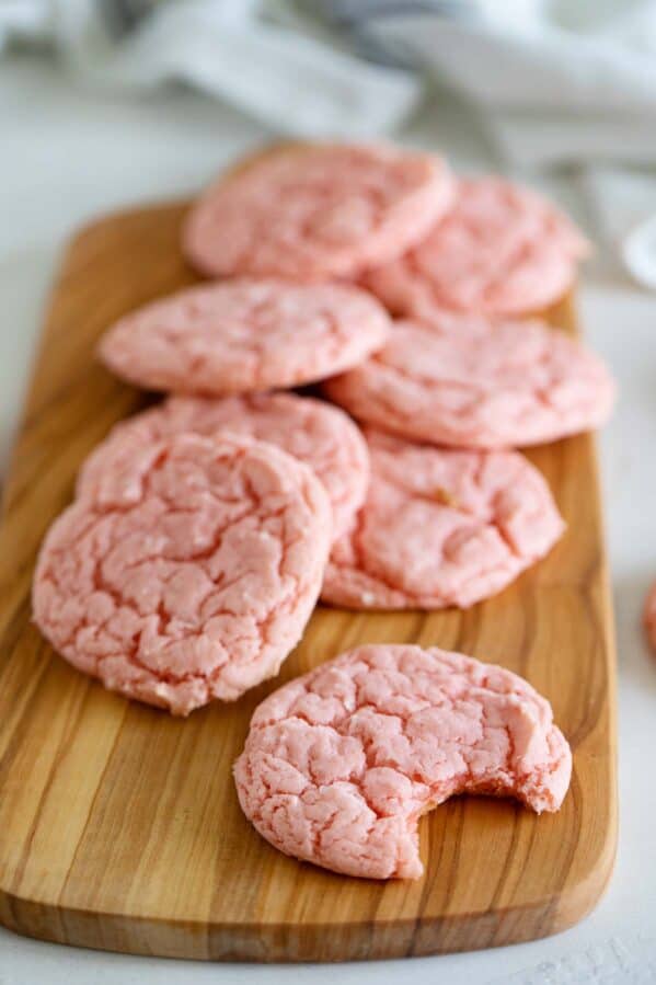 Cake mix cookies made from strawberry cake mix stacked on a cutting board.
