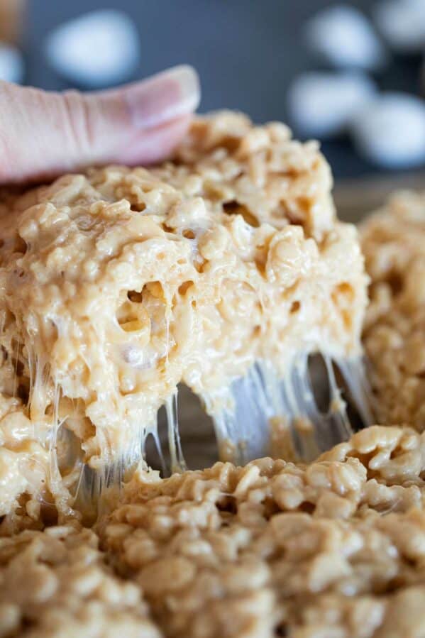 Pulling out a caramel rice krispie showing the gooey marshmallow.