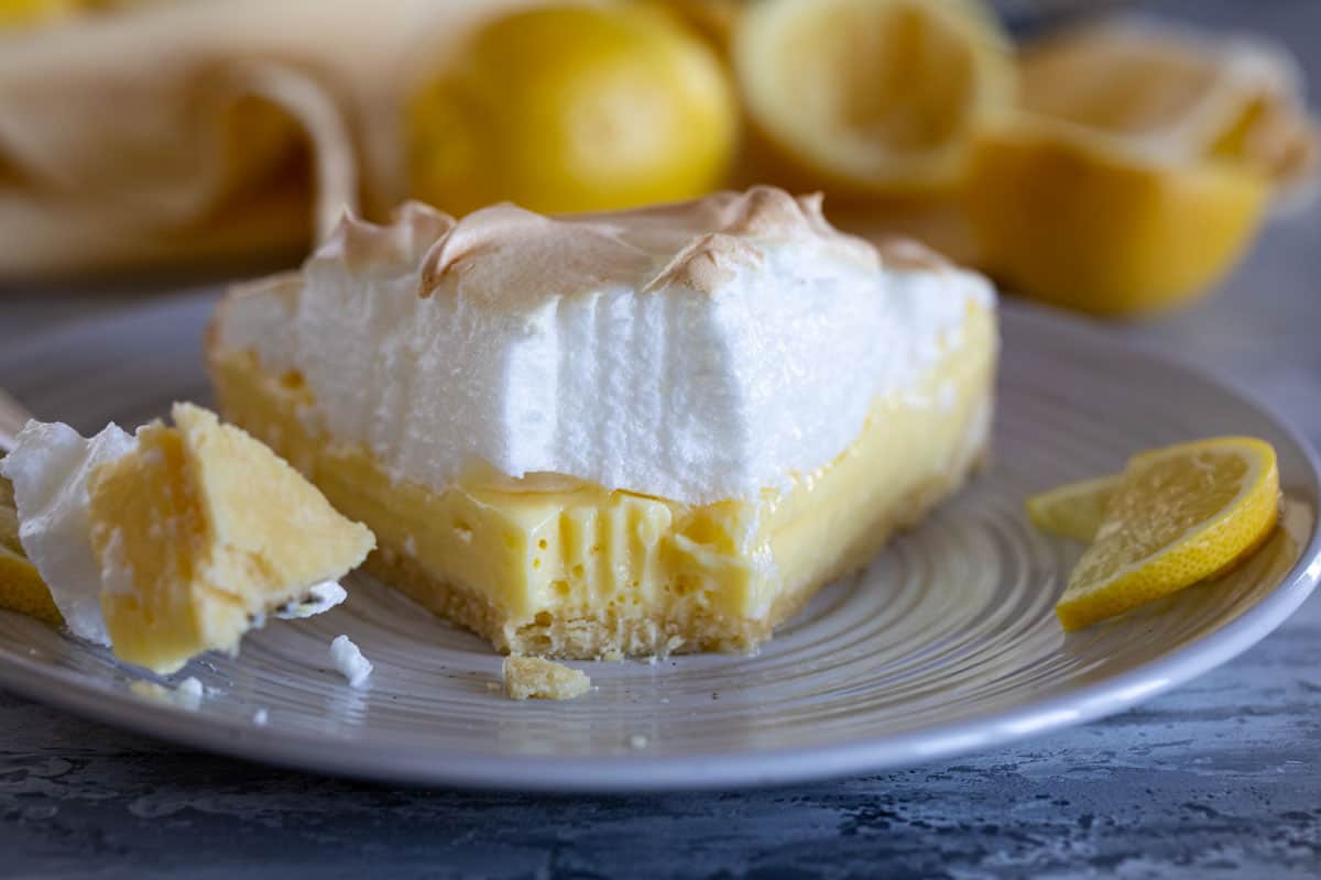 Slice of lemon cream tart with meringue with a bite taken from it.