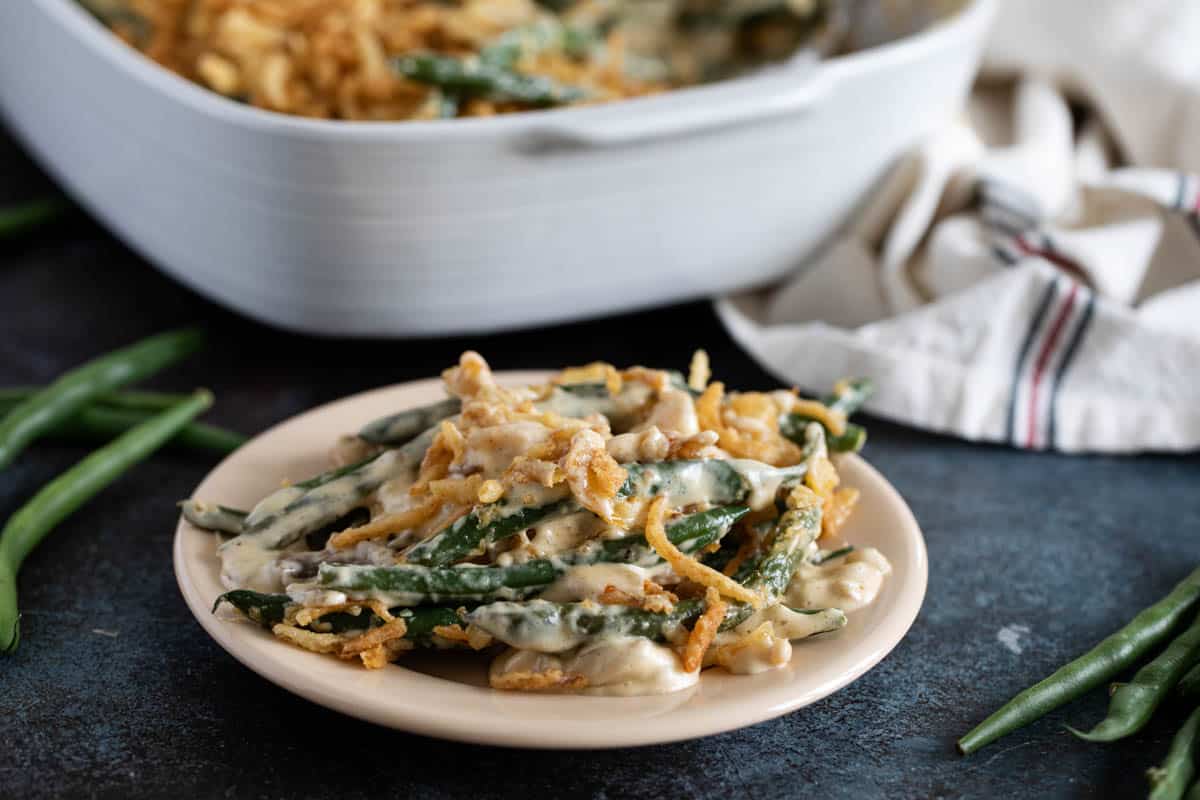 Plate with homemade green bean casserole topped with crispy onion strips.