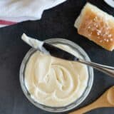 Bowl of honey butter with fresh rolls beside it.