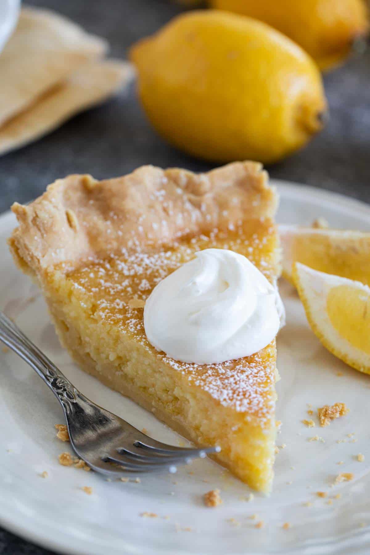 Slice of lemon chess pie topped with whipped cream.