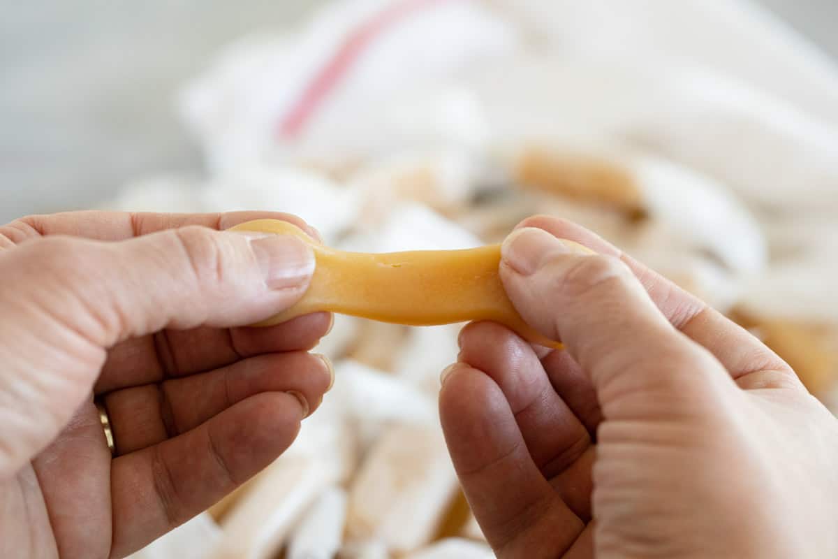 Caramel being stretched apart by two hands.